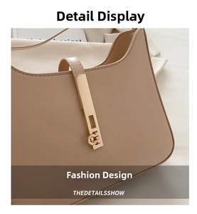 Close-up of beige leather shoulder bag with sleek gold bar metal hardware detail