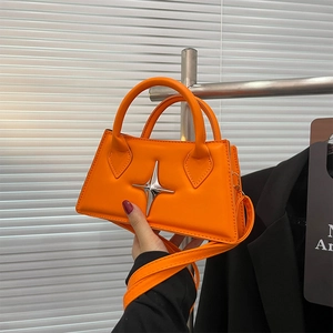 Detail of bright orange square handbag featuring a silver four-point star metal accent