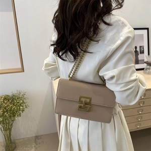 Elegant beige chain shoulder bag with gold geometric clasp shown on a model