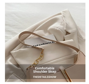 Detail of minimalist beige leather handbag with gold chain strap and metal buckle