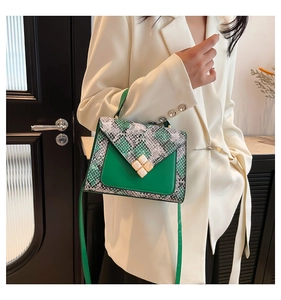 Detail of green leather and snake texture crossbody bag with stone buckle on a model
