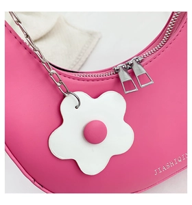 Detail of pink crescent bag with silver chain strap and white flower charm detail