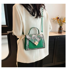 Detail of green crossbody bag with grey snakeskin flap and jewel metal buckle