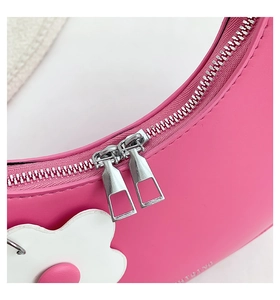 Macro shot of pink crescent leather bag with silver double zippers and flower charm