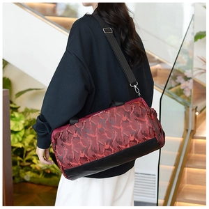 Model wearing a red camo duffel bag with black straps in a modern indoor home setting