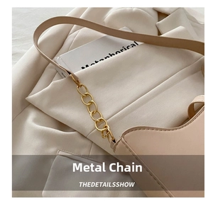 Close-up of beige leather shoulder bag featuring gold chain link hardware and fine stitching