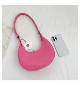 Detail of rose pink crescent hobo bag with white flower pendant and smartphone for size scale