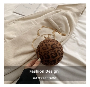 Detail shot of leopard print ball bag featuring a gold ring handle and metal chain strap