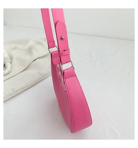 Detail of pink crescent shoulder bag featuring adjustable strap and silver metal zipper
