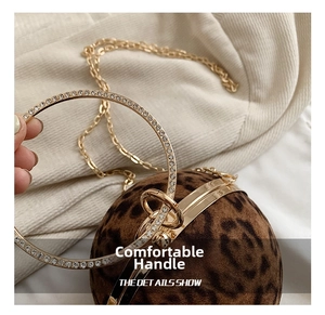 Detail of round leopard print evening bag featuring rhinestone-encrusted metal handles