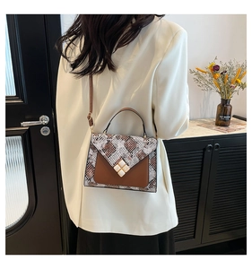 Brown crossbody bag with snake print detail shown on shoulder with white blazer