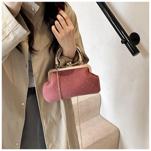 Pink velvet shell bag with crystal dots and round golden handle worn by a model