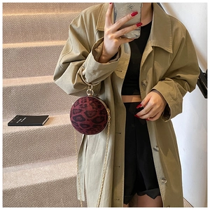 Detail of a leopard print sphere bag with gold metal handle and chain strap on stairs