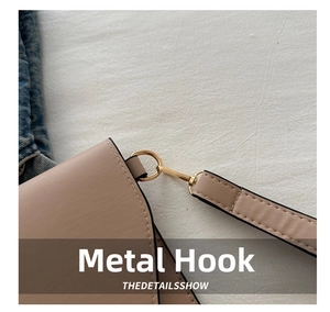 Detailed close-up of the golden metal hook and D-ring on a pale pink leather handbag