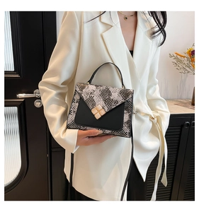 Close-up of snake skin pattern handbag with metal flower buckle on white suit
