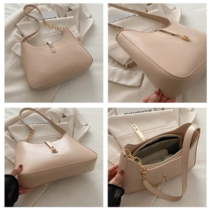 Detail view of cream leather underarm bag with gold piston buckle and chain strap
