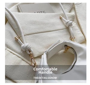 Detail of white half-moon handbag showing smooth leather, gold zipper and knotted handle