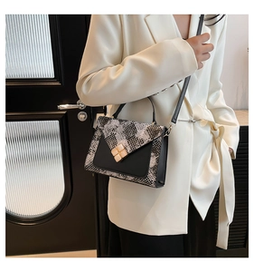 Detail of snake skin pattern texture and golden clover buckle on crossbody bag