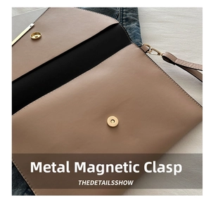 Detail of the golden magnetic snap button closure on a beige envelope clutch bag