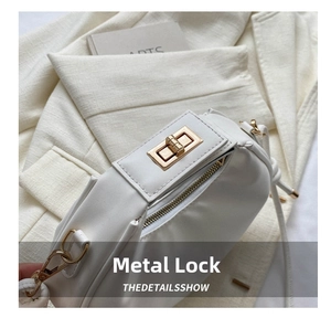 Detailed macro view of the gold rotary hardware lock on a white leather handbag