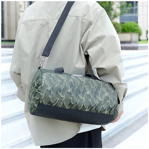 Detailed view of large capacity camo travel bag worn by model on outdoor stone steps