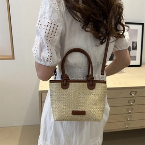 Handwoven straw tote bag with brown leather handles and a long shoulder strap for women