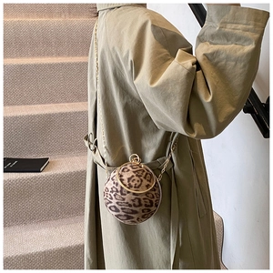 Chic leopard print sphere crossbody bag with golden chain strap on stylish trench coat