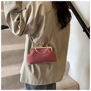 Pink velvet shell bag with white dots and gold chain strap worn as a crossbody