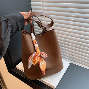 Deep brown pebble leather bucket bag with orange silk scarf and vintage shoulder strap
