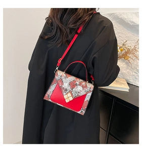 Close-up of snakeskin pattern shoulder bag with a gold clover clasp and red leather accents
