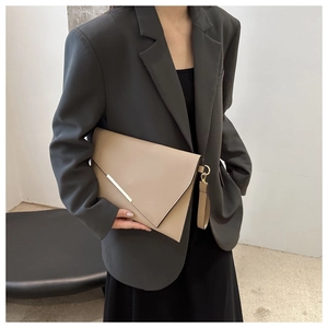 Detail of beige envelope clutch bag with gold metal trim and detachable wristlet strap