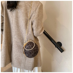 Detail of round leopard print crossbody bag with gold rhinestone handle on wool coat