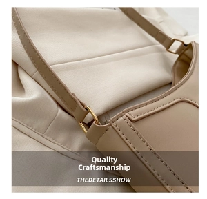 Close-up of golden metal buckle and reinforced stitching on beige leather handbag