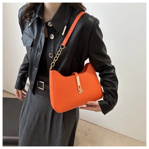 Detail of orange PU leather shoulder bag with gold chain strap and metallic buckle