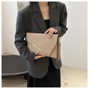 Detail of elegant beige envelope clutch with gold metal trim held by a stylish model