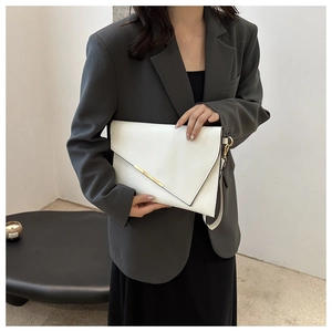 Detail of white envelope clutch bag with gold metal trim and detachable strap