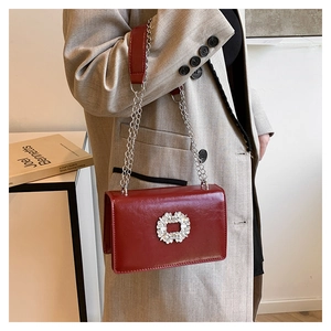 Détail du sac vintage rouge avec boucle en cristal et bandoulière chaîne argentée