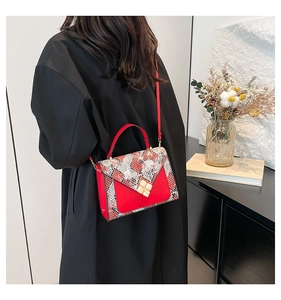 Detail of red leather crossbody bag with snake print flap and gold floral clasp lock