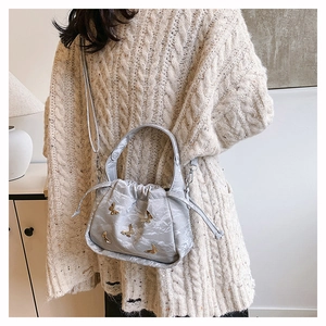 Sac seau gris argenté à cordon avec papillon doré porté par un mannequin