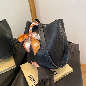 Large black bucket bag in pebble leather with white stitching and floral scarf wrap