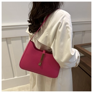 Detail of fuchsia leather hobo bag with gold metal clasp worn by model from a side angle