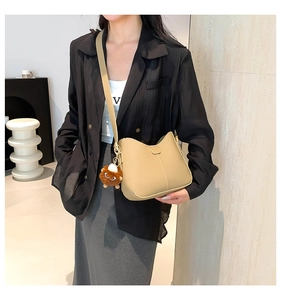 Detail of minimalist beige saddle bag with precise stitching and plush animal charm accessory