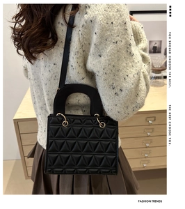 Rear view of black quilted handbag with triangular stitching worn by a model