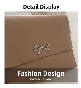 Close-up of beige envelope clutch bag featuring silver bow hardware and fine stitching