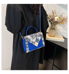 Detail view of blue leather crossbody bag with snake skin pattern and gold metal lock