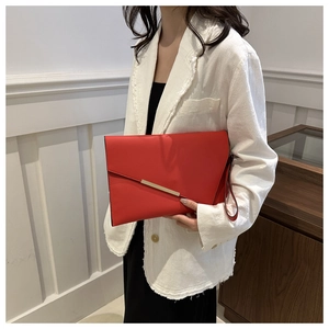 Detail of red leather envelope clutch featuring an asymmetrical flap and gold metal trim