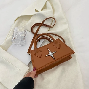 Brown minimalist leather handbag with silver star buckle worn on a white suit jacket