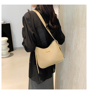 Close-up of beige PU leather bucket bag with FASHION metal logo and vertical stitching