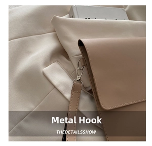 Close-up of silver metal hook and fine stitching detail on beige leather envelope bag