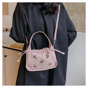 Dettaglio della borsa a secchiello rosa con farfalle dorate e chiusura a coulisse
